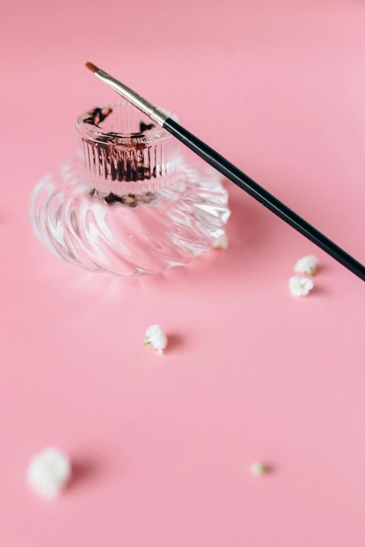 a brush sitting on top of a glass container, by Julia Pishtar, trending on unsplash, magic realism, pink background, chopsticks, delicate embellishments, smoking