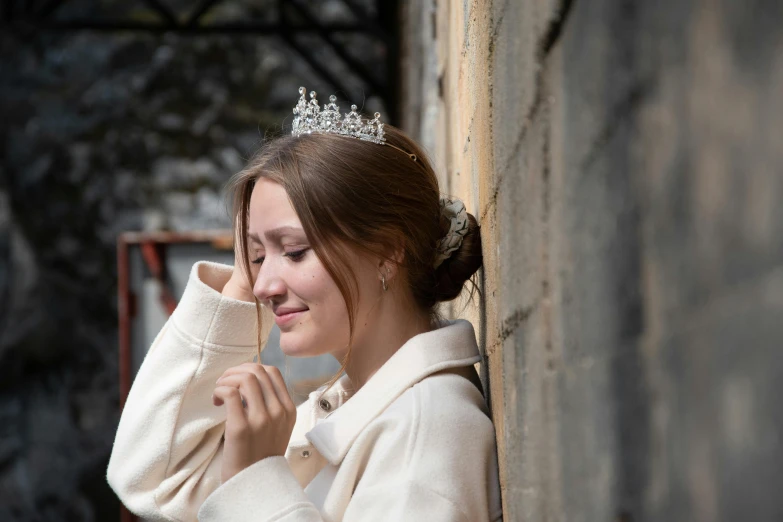 a woman wearing a tiara leaning against a wall, by Alice Mason, trending on unsplash, silver，ivory, environmental shot, wearing a royal robe, girl sitting on a rooftop