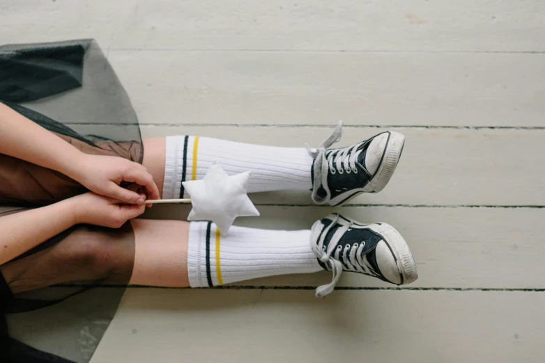 a person sitting on top of a wooden floor, inspired by Sarah Lucas, pexels, shooting star, white and yellow scheme, little kid, socks