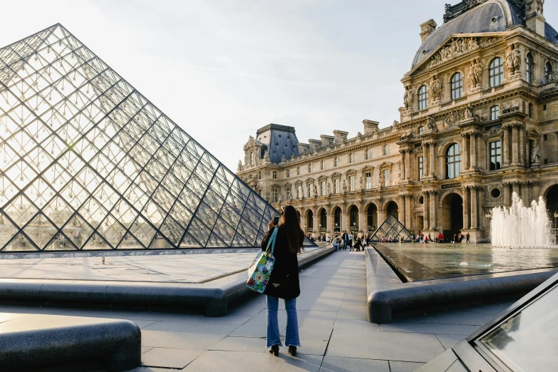 a woman standing in front of a glass pyramid, a photo, by Julia Pishtar, pexels contest winner, ornate french architecture, rem koolhaas, monalisa, a person standing in front of a