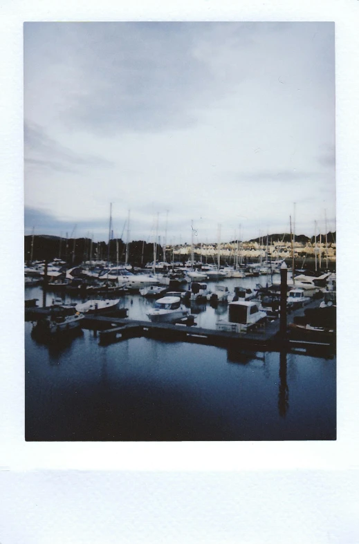 a harbor filled with lots of boats under a cloudy sky, a polaroid photo, inspired by Thomas Struth, vsco, medium format, conor walton, calm evening