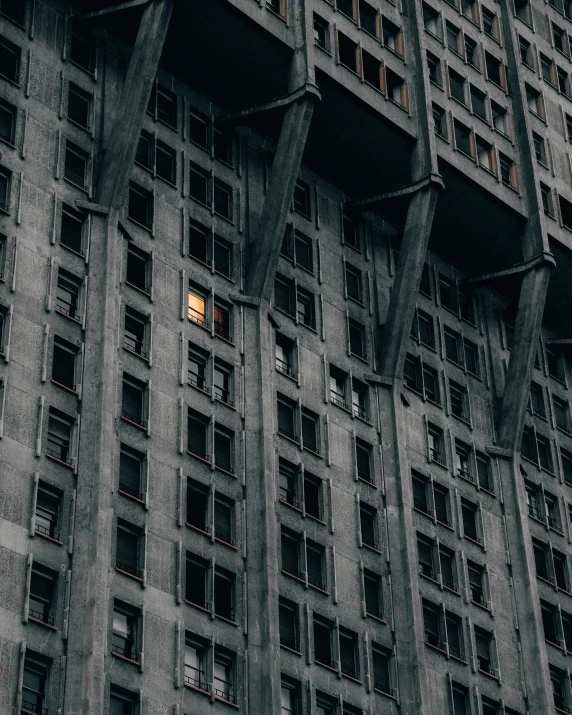 a black and white photo of a tall building, inspired by Elsa Bleda, unsplash contest winner, brutalism, open window at night, yellow windows and details, 1910s architecture, mossy buildings