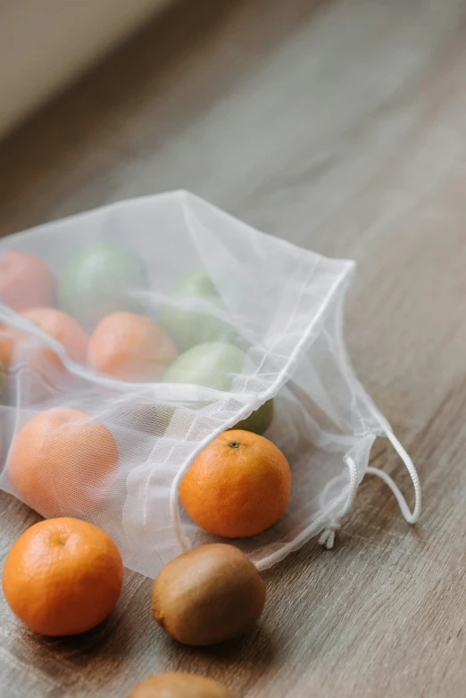 a bag of oranges and kiwis on a table, by Andries Stock, unsplash, netting, soft diffused light, white, 6 pack