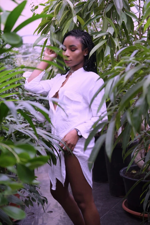 a woman in a white shirt standing in a greenhouse, an album cover, unsplash, visual art, nicki minaj curvy, amongst foliage, wearing a white button up shirt, in robes