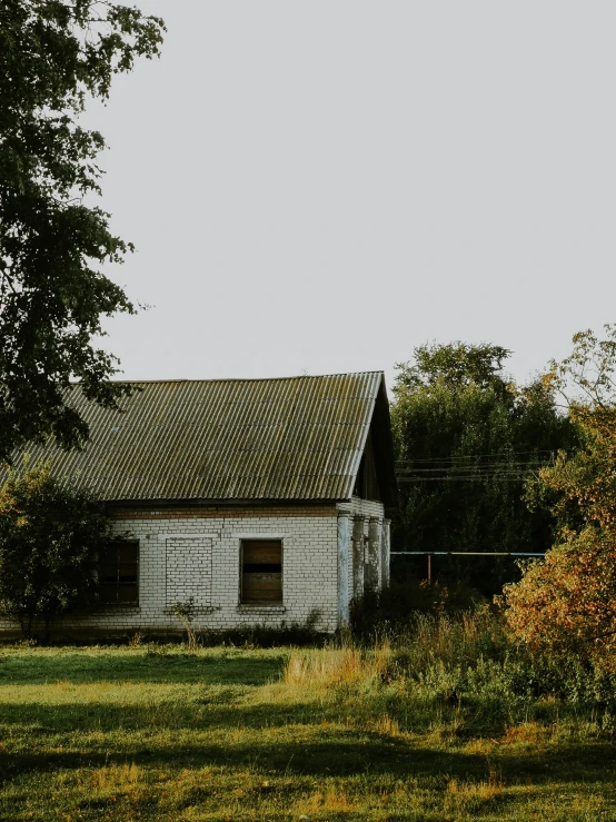 a white house sitting on top of a lush green field, inspired by Isaac Levitan, pexels contest winner, rustic and weathered, brown, evening sunlight, фото девушка курит