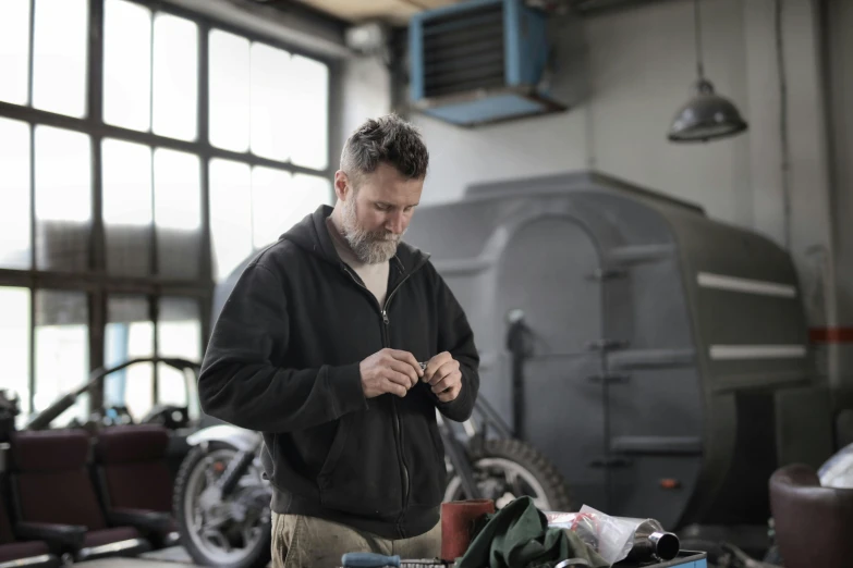 a man working on a motorcycle in a garage, a portrait, pexels contest winner, renaissance, tailored clothing, avatar image, grey, dressed in a worn