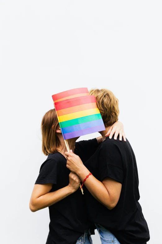 a man and a woman holding a rainbow flag, unsplash, antipodeans, plain background, hugging, 🚿🗝📝
