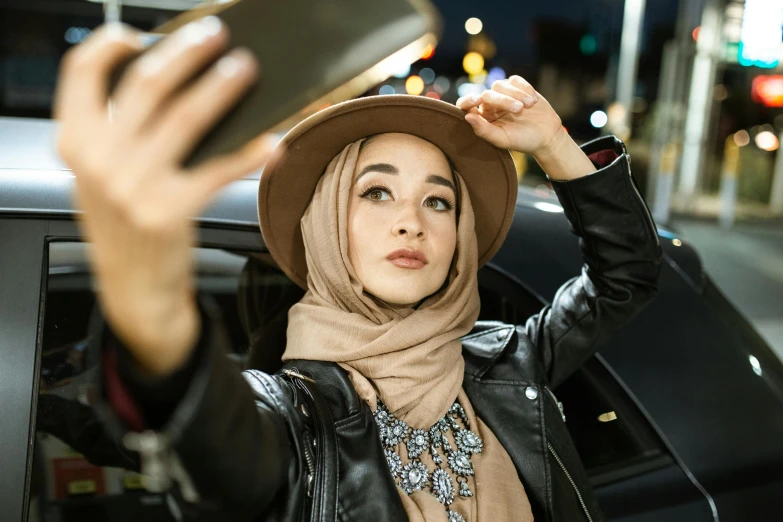 a woman taking a picture of herself in a car, trending on pexels, hurufiyya, hijab, an oversized beret, (night), actress