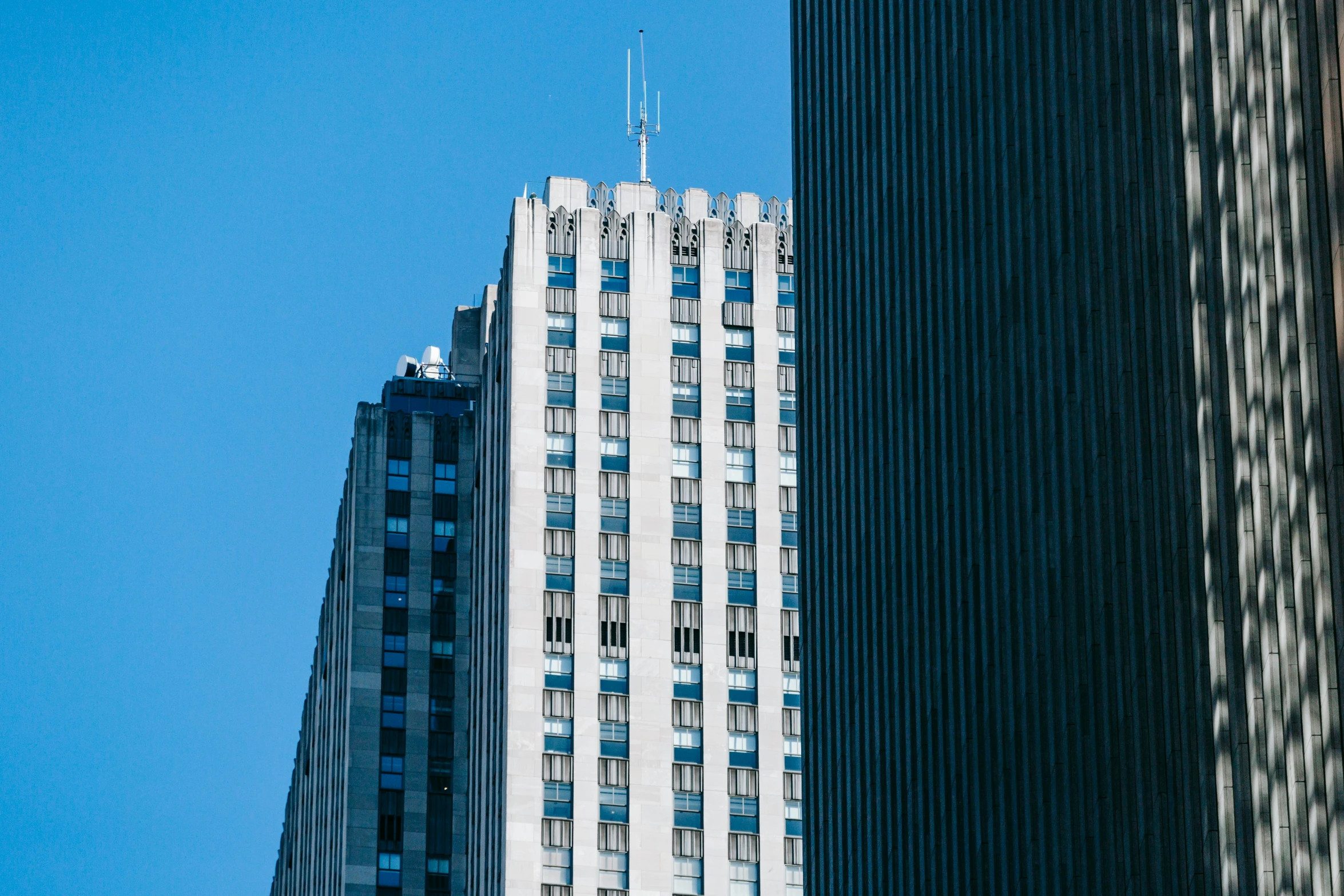 a couple of tall buildings next to each other, by William Woodward, pexels contest winner, modernism, clear blue sky, minimalist rule of thirds, 1980s photo, no - text no - logo