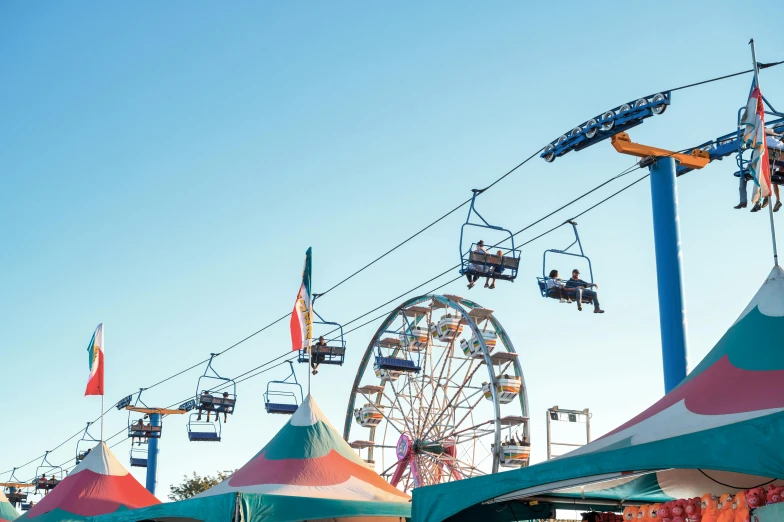 a bunch of tents with a ferris in the background, pexels contest winner, clear blue skies, chairlifts, avatar image, fair