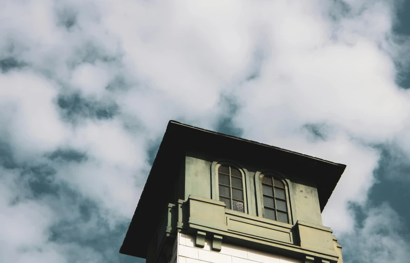 a clock that is on the side of a building, an album cover, unsplash, postminimalism, tall fluffy clouds, muted green, 1910s architecture, lookout tower