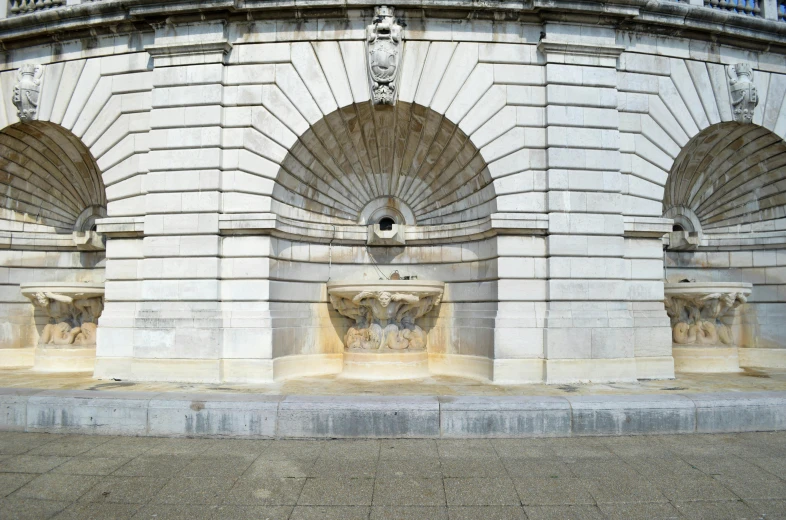 a couple of water fountains sitting on top of a sidewalk, a marble sculpture, inspired by Ian Hamilton Finlay, unsplash, neoclassicism, massive arch, government archive photograph, front view 2 0 0 0, royal relief