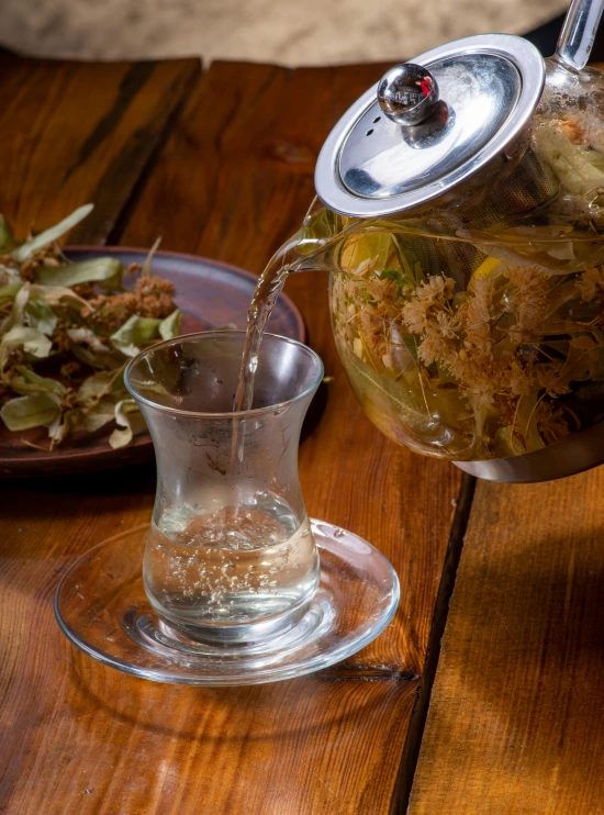 a tea pot filled with food sitting on top of a wooden table, hurufiyya, chaotic gold leaf flowers, thumbnail, absinthe, chilean