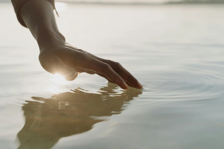 a person touching the surface of a body of water, by Jessie Algie, trending on unsplash, fan favorite, light toned, sydney hanson, curiosity