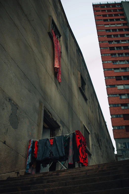 clothes hanging out to dry on a clothes line, an album cover, inspired by Elsa Bleda, brutalism, street of moscow, red bandana, crumbling ancient skyscrapers, rainy; 90's photograph