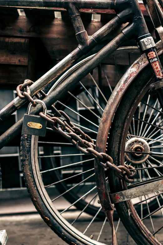 a close up of a bike parked in front of a building, assemblage, rusty chain fencing, on a dark background, brass wheels, crypto