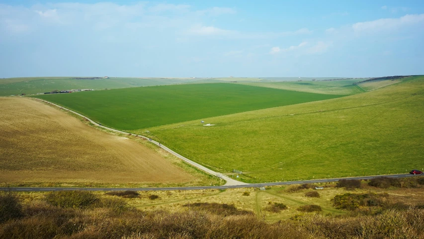 a car driving down a winding country road, an album cover, by Matthias Stom, pexels contest winner, land art, an expansive grassy plain, seaview, madgwick, overview