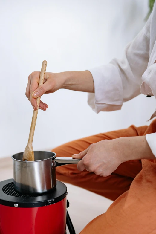 a woman stirring a pot with a wooden spoon, inspired by Inshō Dōmoto, trending on unsplash, wearing silver silk robe, caramel, rectangle, slightly minimal