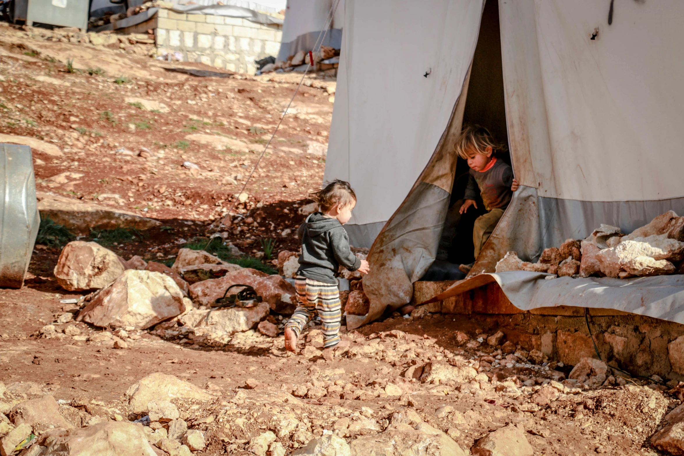 a woman and a child standing outside of a tent, by Daren Bader, trending on unsplash, hurufiyya, destroyed human structures, lebanon kirsten dunst, slide show, australian