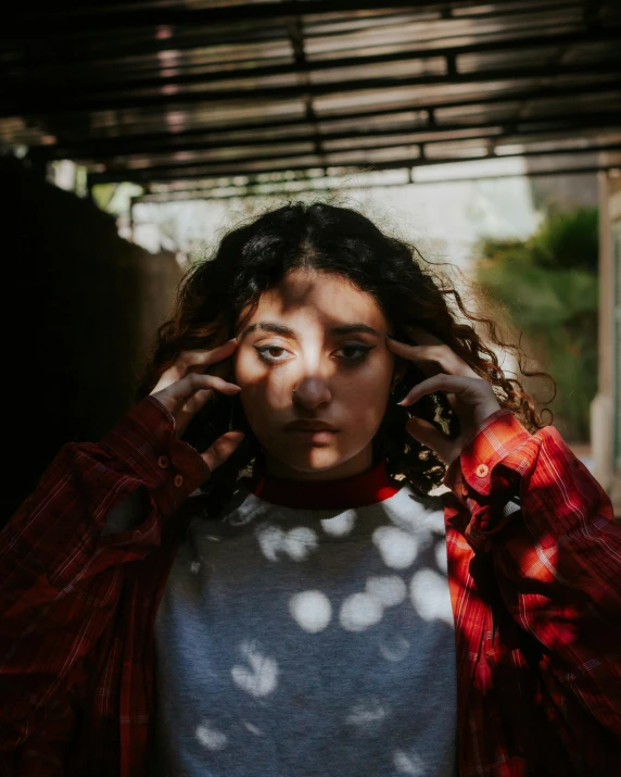 a woman with curly hair talking on a cell phone, a polaroid photo, inspired by Elsa Bleda, trending on pexels, soft grey and red natural light, standing under a beam of light, piercing glare in the eyes, non binary model