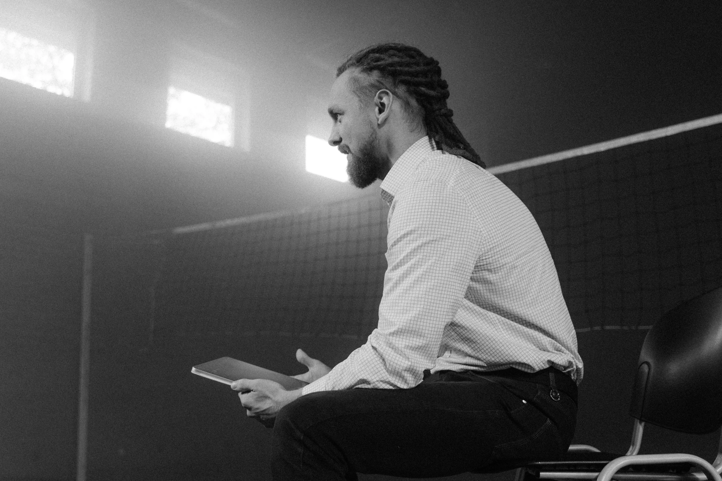 a black and white photo of a man sitting on a chair, unsplash, wearing a volleyball jersey, braided beard redhead dreadlocks, technology, conor mcgregor