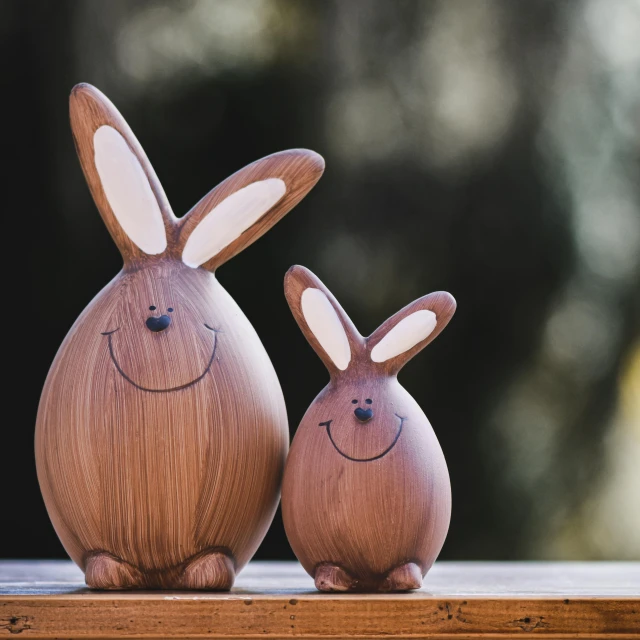 a couple of wooden bunnies sitting on top of a table, a portrait, by Elaine Hamilton, unsplash, large smile, beautiful smooth oval head, wooden banks, happy big chungus