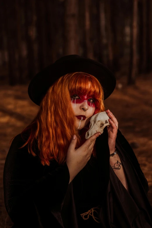 a woman with red hair holding a skull in a forest, pexels contest winner, lowbrow, black witch hat, an ewok eating a lollipop, profile image, drag