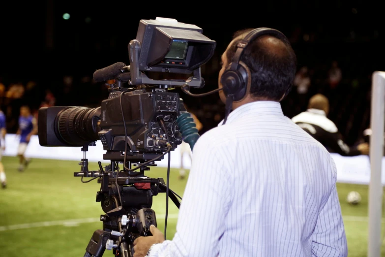 a man that is standing in front of a camera, happening, on the field, television head, back towards camera, sports