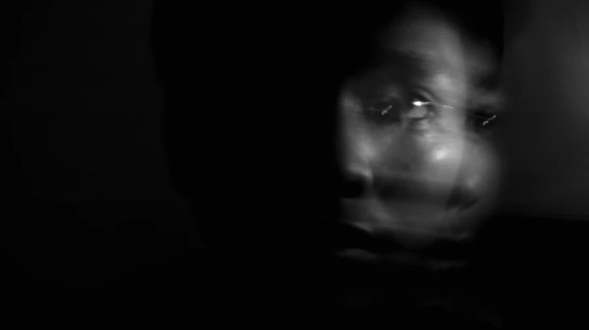 a black and white photo of a person in the dark, inspired by Carrie Mae Weems, surrealism, zoom on alien face, still from a terence malik film, david uzochukwu, person made out of glass