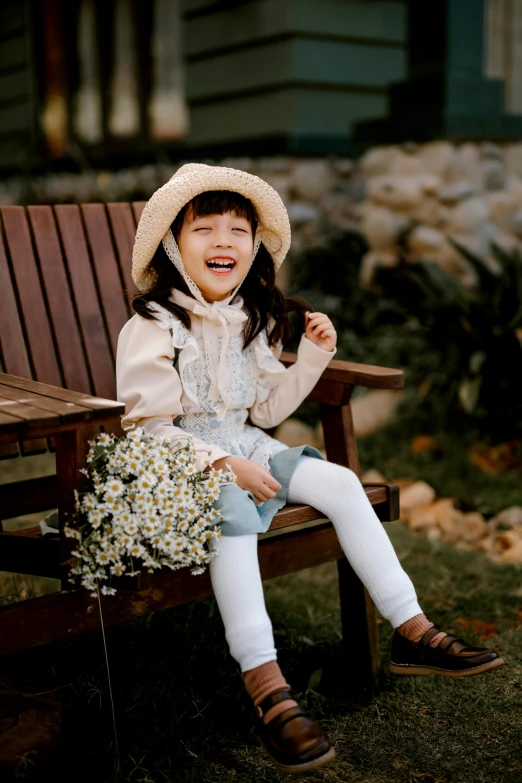 a little girl sitting on top of a wooden bench, inspired by Cui Bai, pexels contest winner, playful smile, in style of lam manh, holding daisy, in a comfortable chair