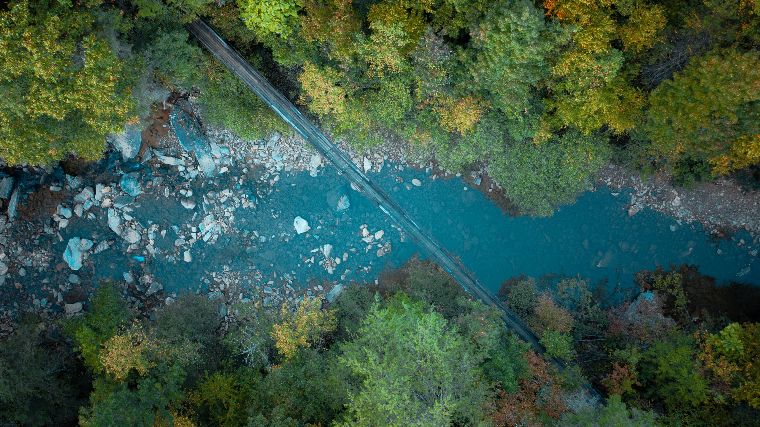 an aerial view of a river surrounded by trees, inspired by Elsa Bleda, pexels contest winner, hurufiyya, bridge, blue and cyan colors, thumbnail, switzerland