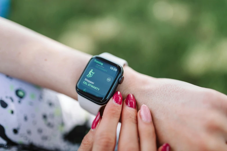 a close up of a person holding an apple watch, by Adam Marczyński, pexels, green and pink, square, woman, talking