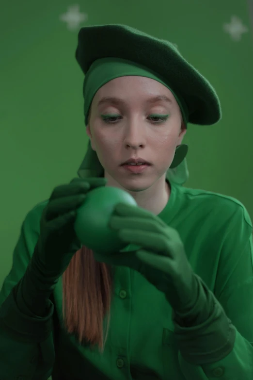 a woman in a green outfit holding a green apple, inspired by Art Green, trending on pexels, magic realism, live-action archival footage, berets, saoirse ronan, casting a protection spell