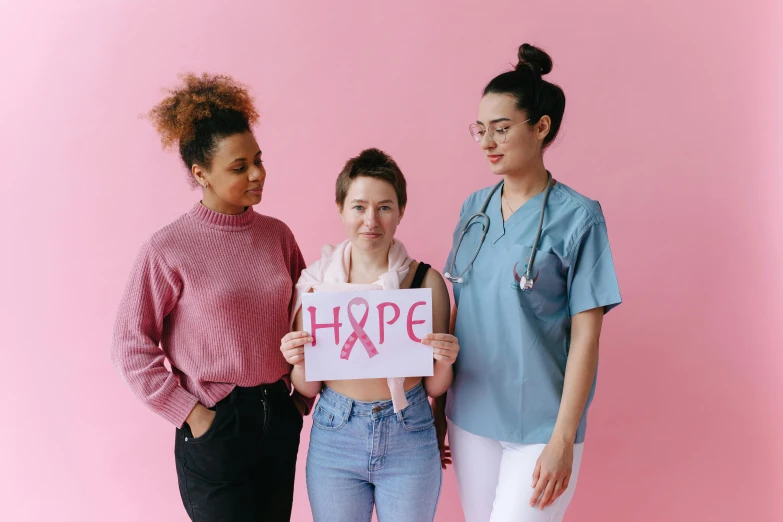 three women standing next to each other holding a sign, trending on pexels, antipodeans, stethoscope, ((pink)), hope, white ribbon