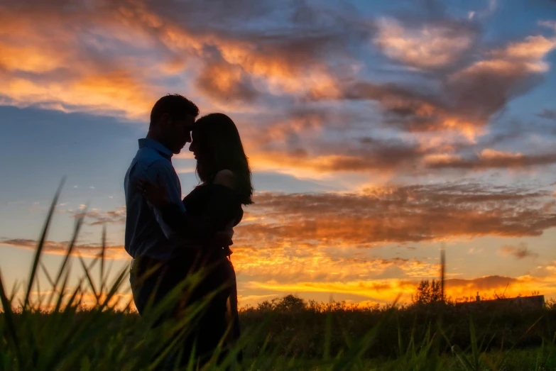 a couple kissing in a field at sunset, by Matt Cavotta, pexels contest winner, vivid sky, profile image, coloured photo, a single