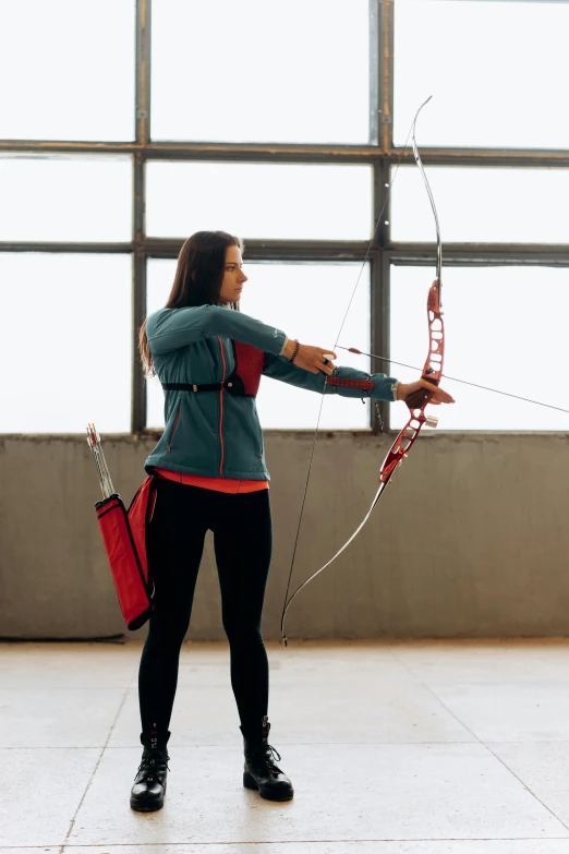 a woman holding a bow and arrow in front of a window, pexels contest winner, arabesque, in a gym, curved red arrow, in an arena pit, promo image