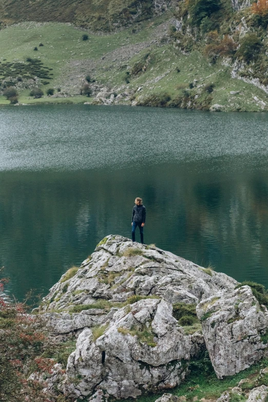 a man standing on top of a rock next to a lake, les nabis, girl of the alps, carola rubio, guide, secluded