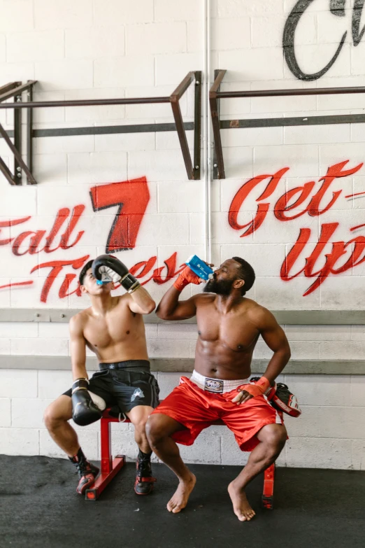 two men sitting next to each other in a gym, by Kaff Gerrard, drunken boxing, fall guys, energy drink, 6 pack ab