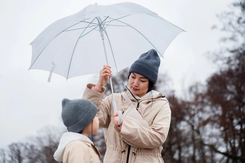 a woman standing next to a boy holding an umbrella, pexels contest winner, he also wears a grey beanie, opening scene, promotional image, rain sensor