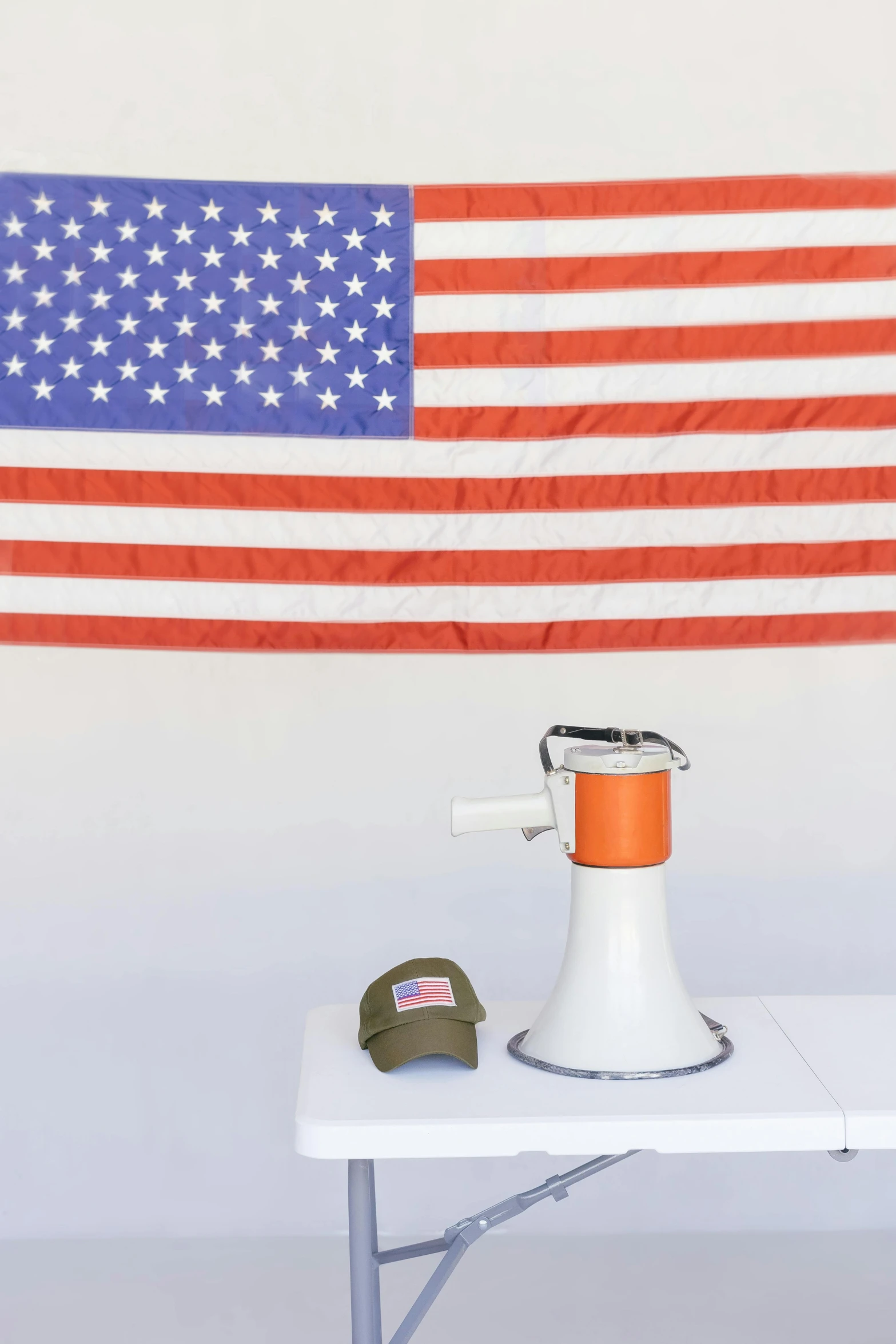 a fire hydrant sitting on top of a table next to an american flag, a portrait, unsplash, white and orange, standing microphones, military, photo courtesy museum of art