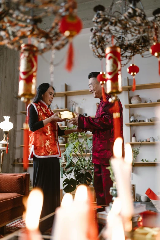 a couple of people that are standing in a room, inspired by Cui Bai, happening, festive atmosphere, square, traditional, candles