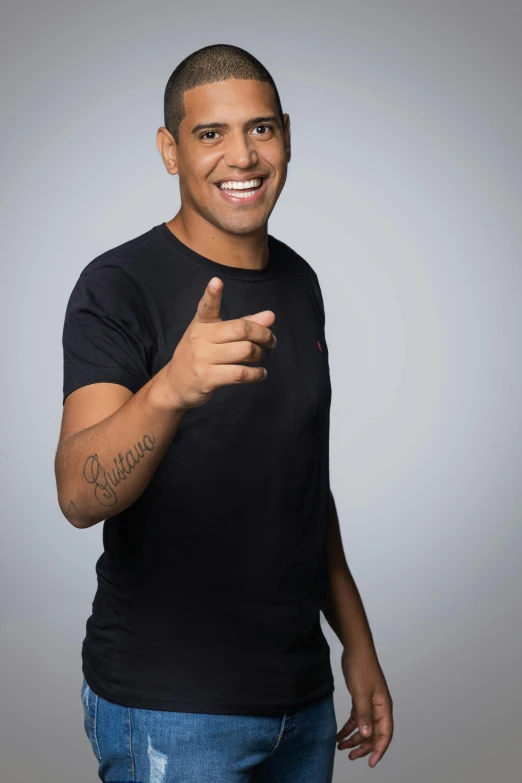 a man in a black shirt giving a thumbs up, by Christopher Williams, in a photo studio, ariel perez, smileing nright, taken in the early 2020s
