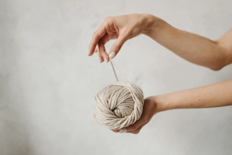 a person holding a ball of yarn in their hands, trending on pexels, beige cream natural muted tones, limestone, full product shot, frontal shot