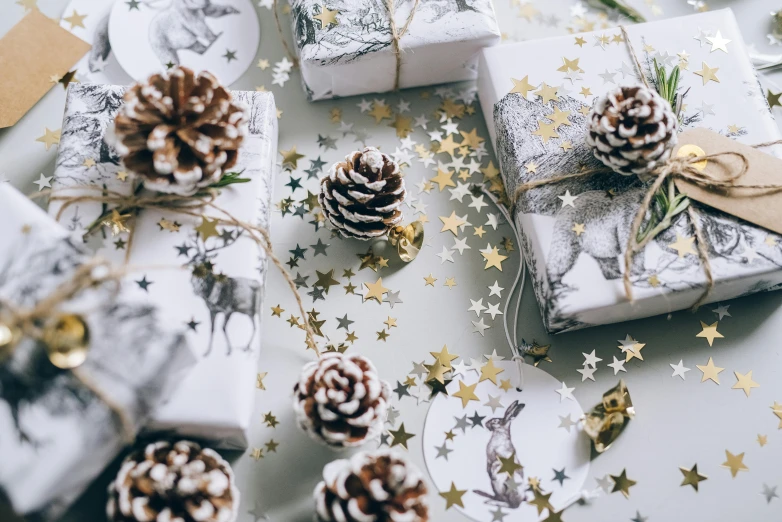 a table topped with wrapped presents and pine cones, trending on pexels, process art, tiny stars, white with gold accents, thumbnail, close - up portrait shot