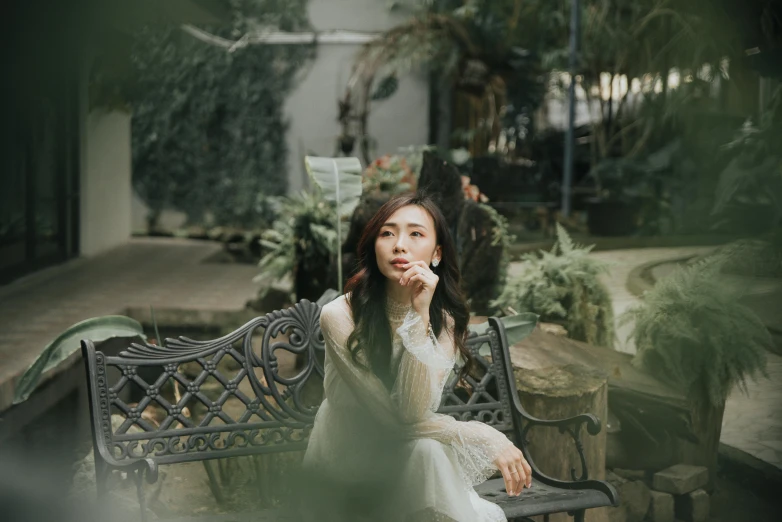 a woman sitting on a bench talking on a cell phone, inspired by Kim Du-ryang, pexels contest winner, rococo, natural beauty expressive pose, botanic garden, dang my linh, elegant lady with alabaster skin