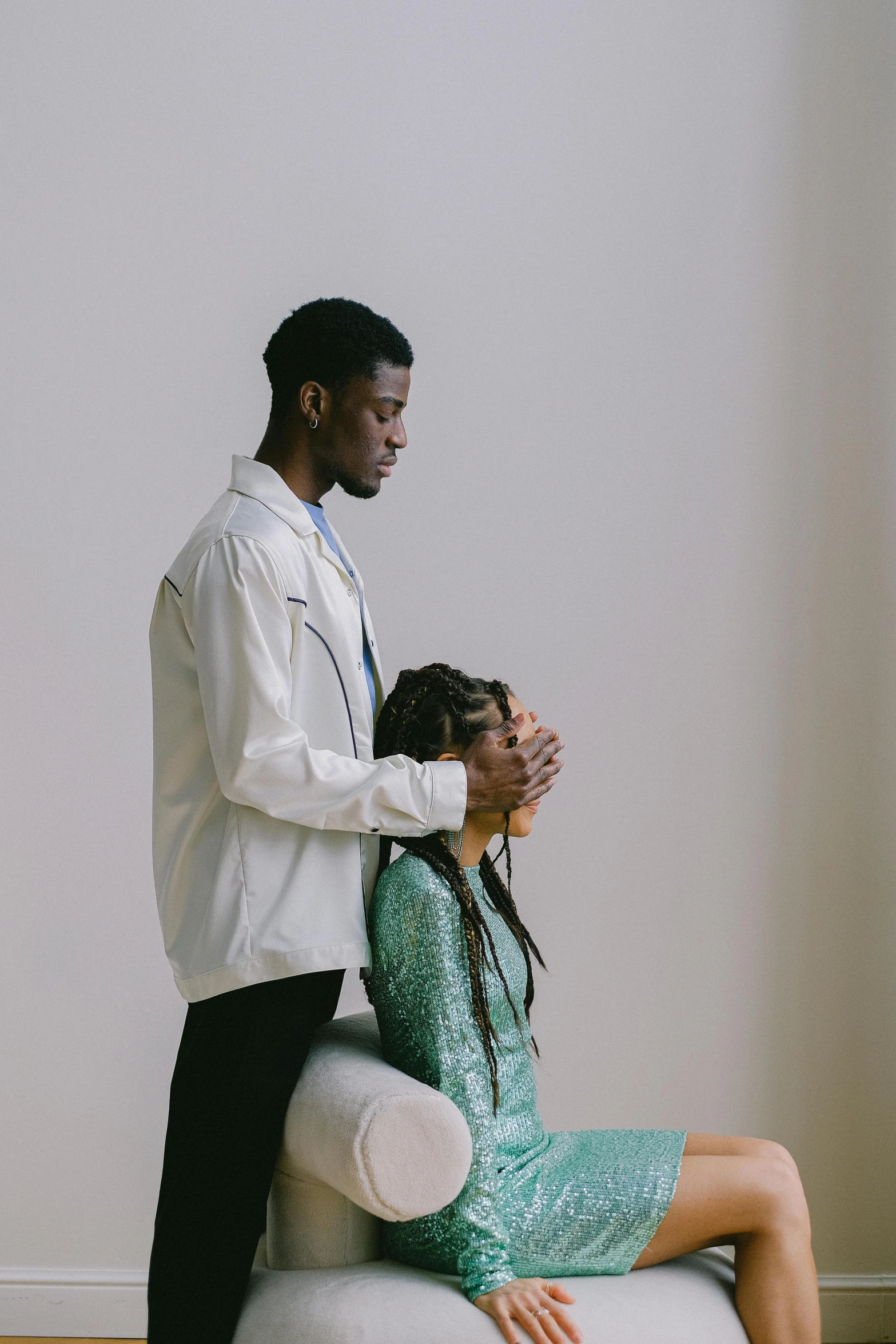 a man standing next to a woman in a green dress, by Jessie Algie, trending on unsplash, praying posture, black human spine, wearing lab coat and a blouse, sitting pose