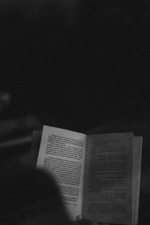 a person reading a book in a dark room, a black and white photo, inspired by Roy DeCarava, unsplash, vhs screencap, ✨🕌🌙, lofi aesthetic, concert