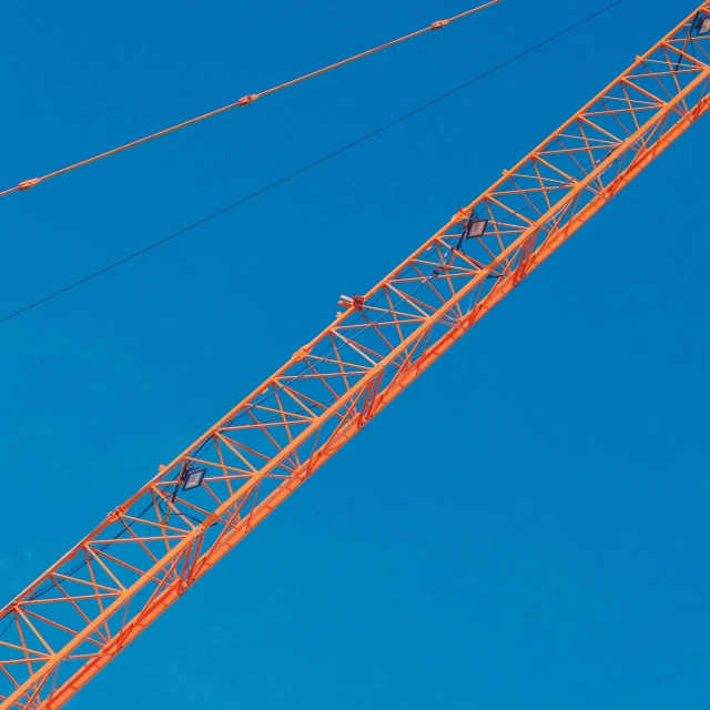 a crane sitting on top of a building under a blue sky, by Jan Rustem, pexels contest winner, constructivism, blue!! with orange details, solid color background intricate, high angle close up shot, camaraderie