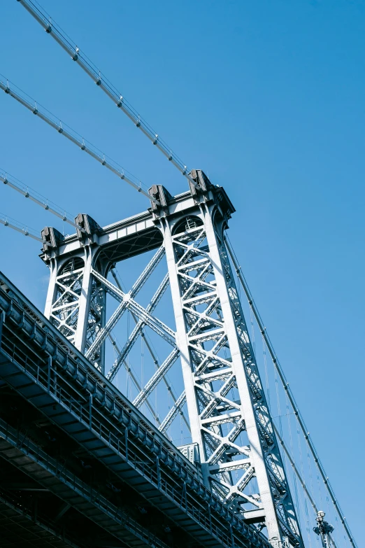 a bridge over a body of water under a blue sky, inspired by William Berra, unsplash, graffiti, tall metal towers, harlem, 1999 photograph, wrought iron architecture