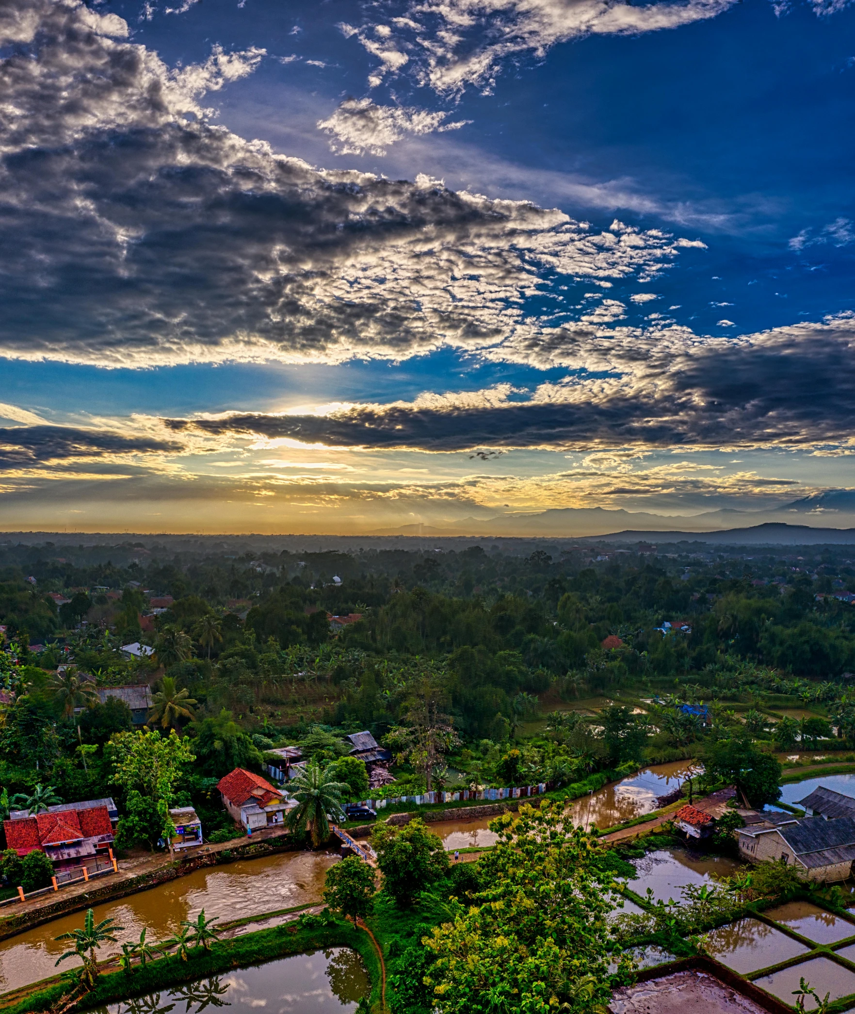 a river running through a lush green countryside, a picture, unsplash contest winner, sumatraism, vista of a city at sunset, square, cambodia, blue sky